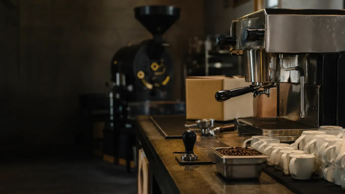 Espressomaschine, Kaffeemühle und Trommelröster nebeneinander in einer Rösterei